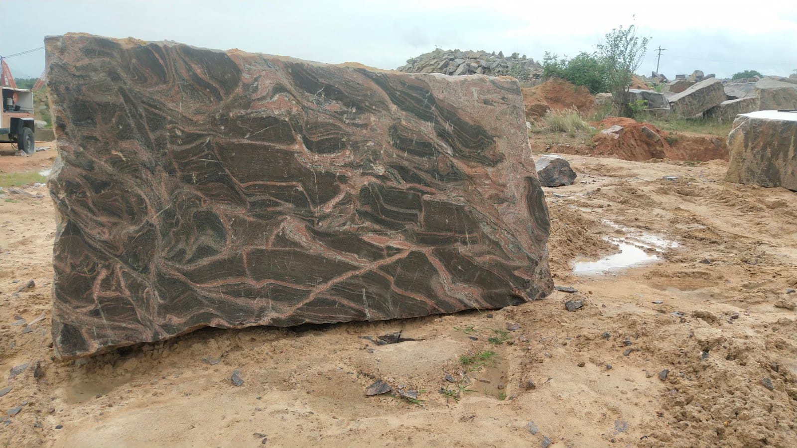 Rough stone block in quarry yard after rain